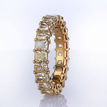 Natural fancy yellow radiant cut diamond eternity band set in 18kt yellow gold airline basket setting with shared claw prong design. 